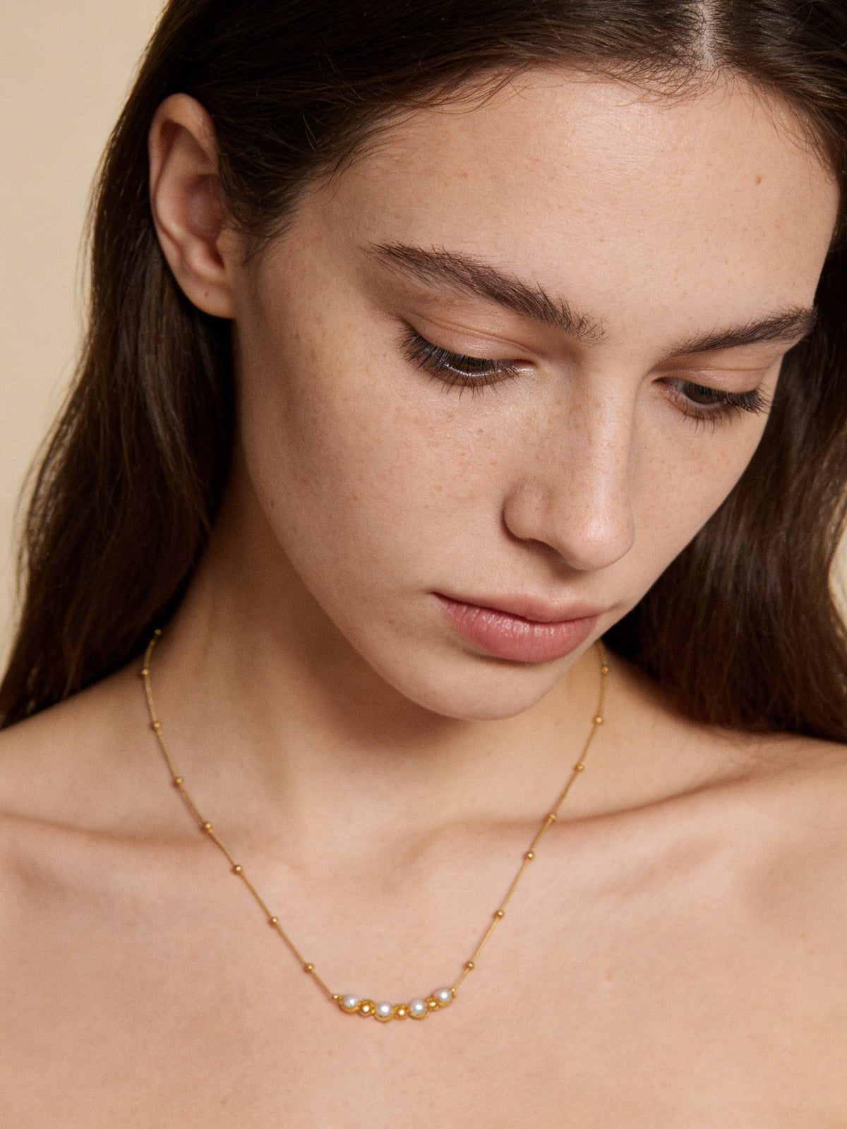Accent Beaded Choker Necklace in gold with faux pearls, shown on a model looking down