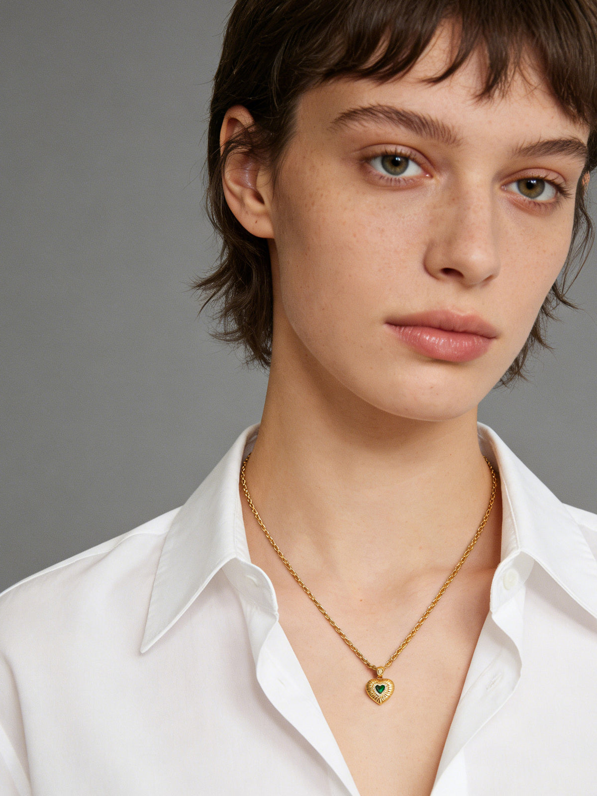 Emerald Heart Pendant Necklace in gold with a green heart, shown on a model, front view