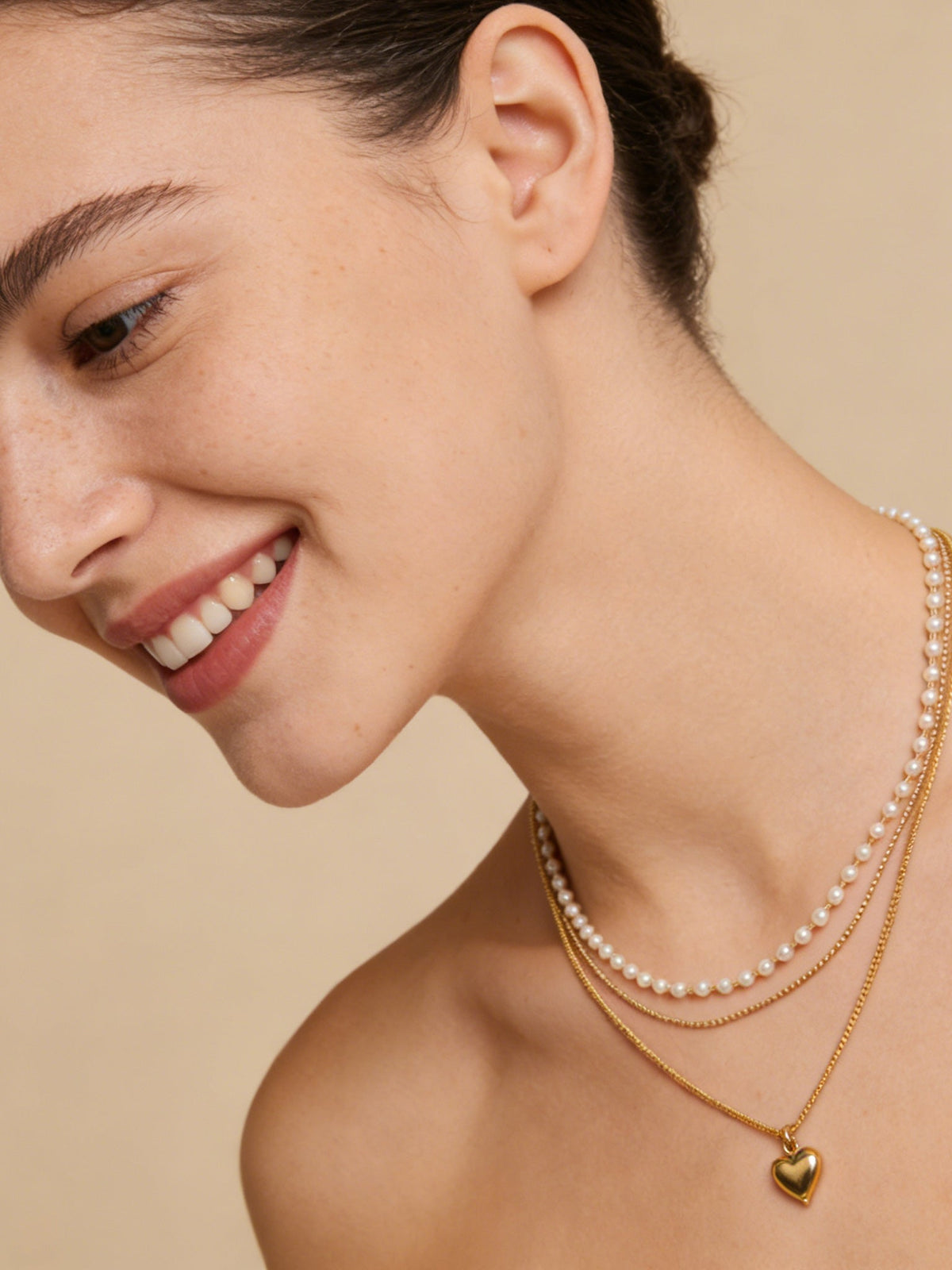 Layered Heart Pendant Necklace in gold with faux pearls, shown on a model, three-quarter view