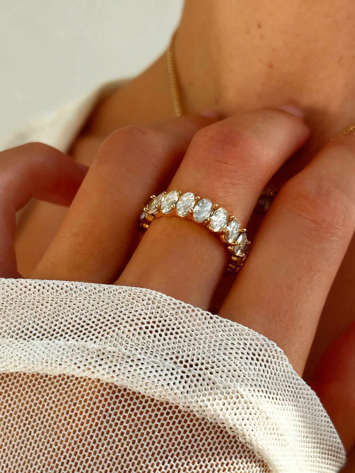 The Luminous Embrace Oval Eternity Ring in gold with clear stones, shown on a model, close up