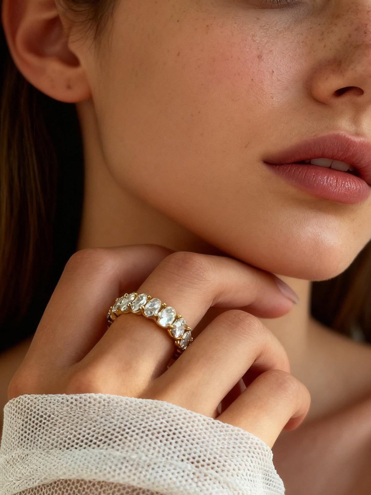 The Luminous Embrace Oval Eternity Ring in gold with clear stones, shown on a model, close up